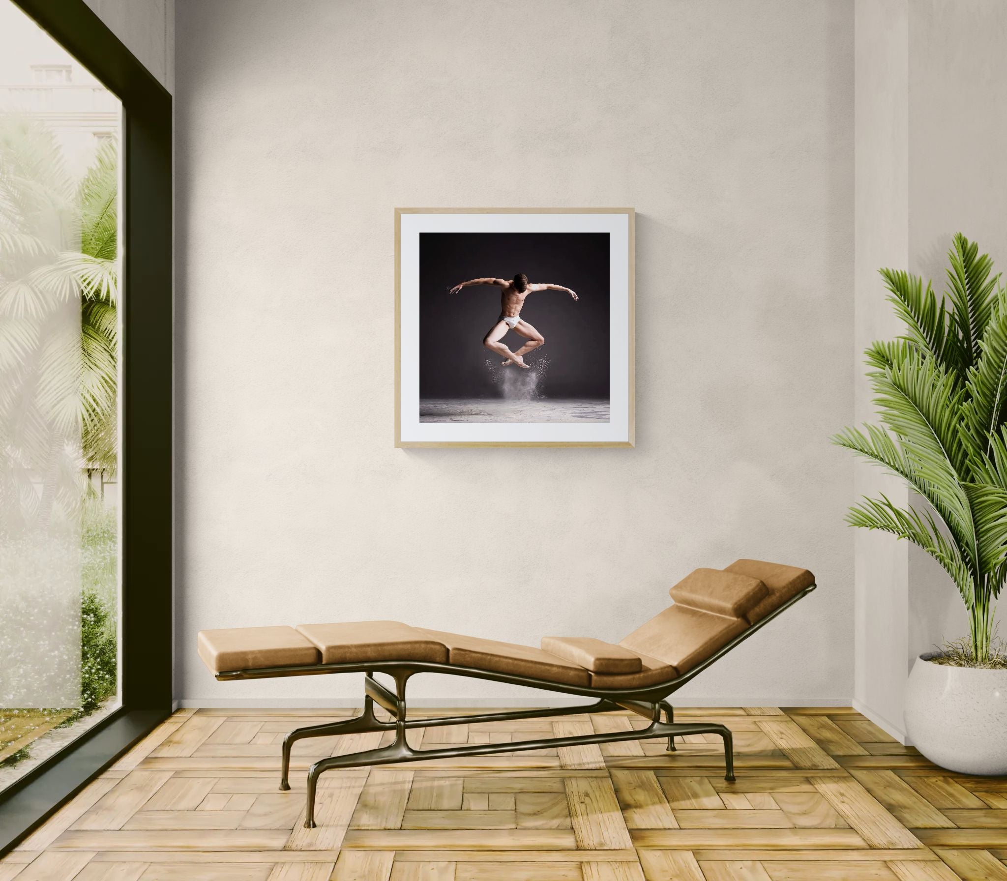 Framed Cloud Dancer – Powder Leap print above a tan chaise lounge in a bright room with pale walls, wood floor and large green plant.