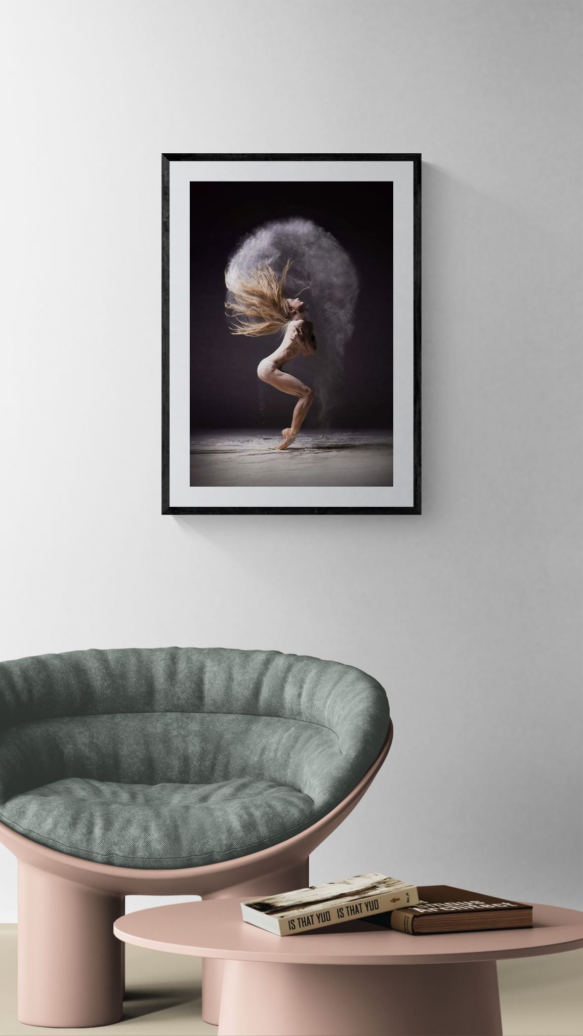 Framed Cloud Halo dance photograph hanging above a rounded green chair and pink low table in a minimalist living room.