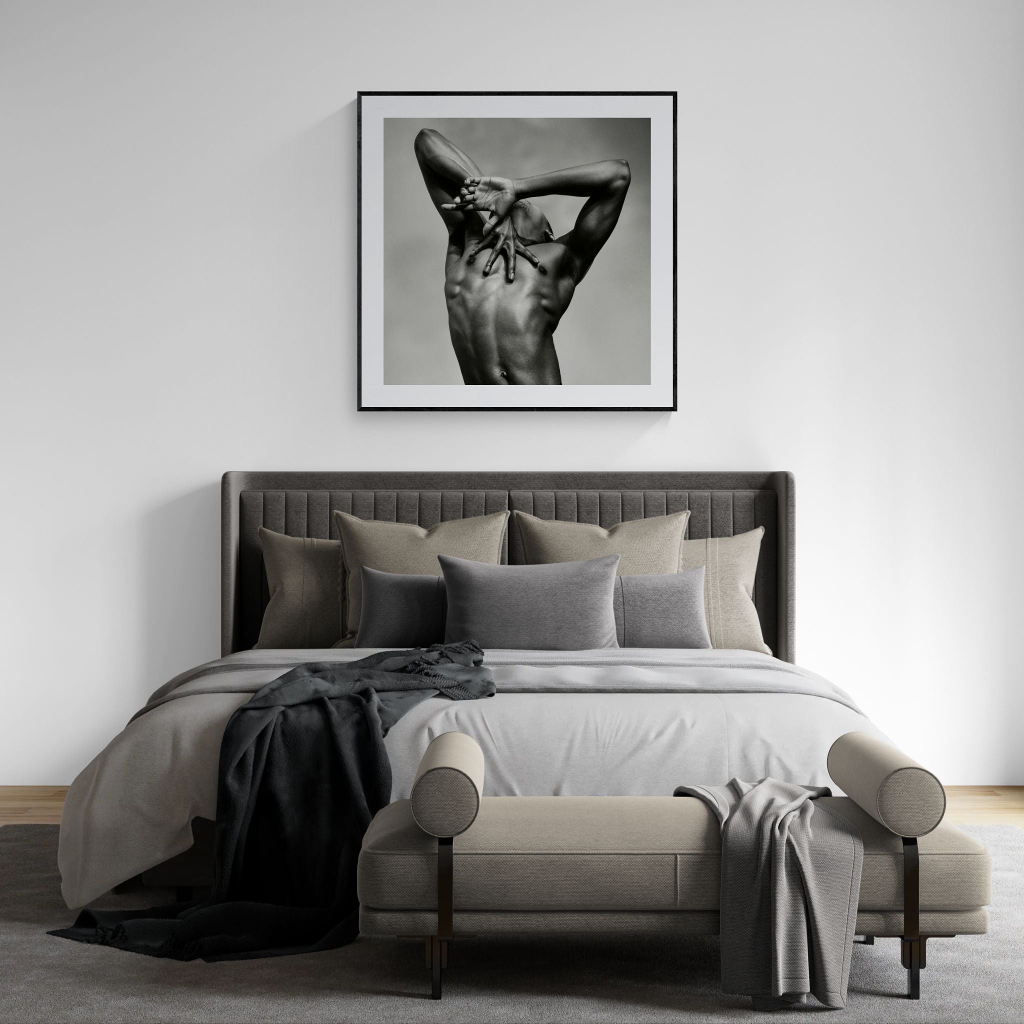 Large framed J. print by Sasha Onyshchenko showcased above a light grey upholstered bed in a luxury minimalist bedroom with layered neutral textiles.