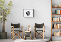 Two director's chairs with a small table in a room with a bookshelf and plant.