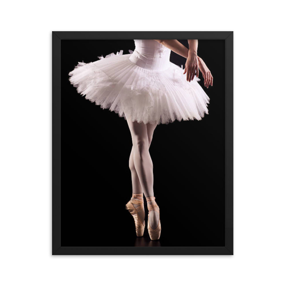 Framed fine art poster titled 'Ballerina En-Pointe,' showcasing the lower body of a poised ballerina on pointe wearing a delicate white tutu. Captured against a dramatic black backdrop, this artwork embodies elegance and timeless grace.