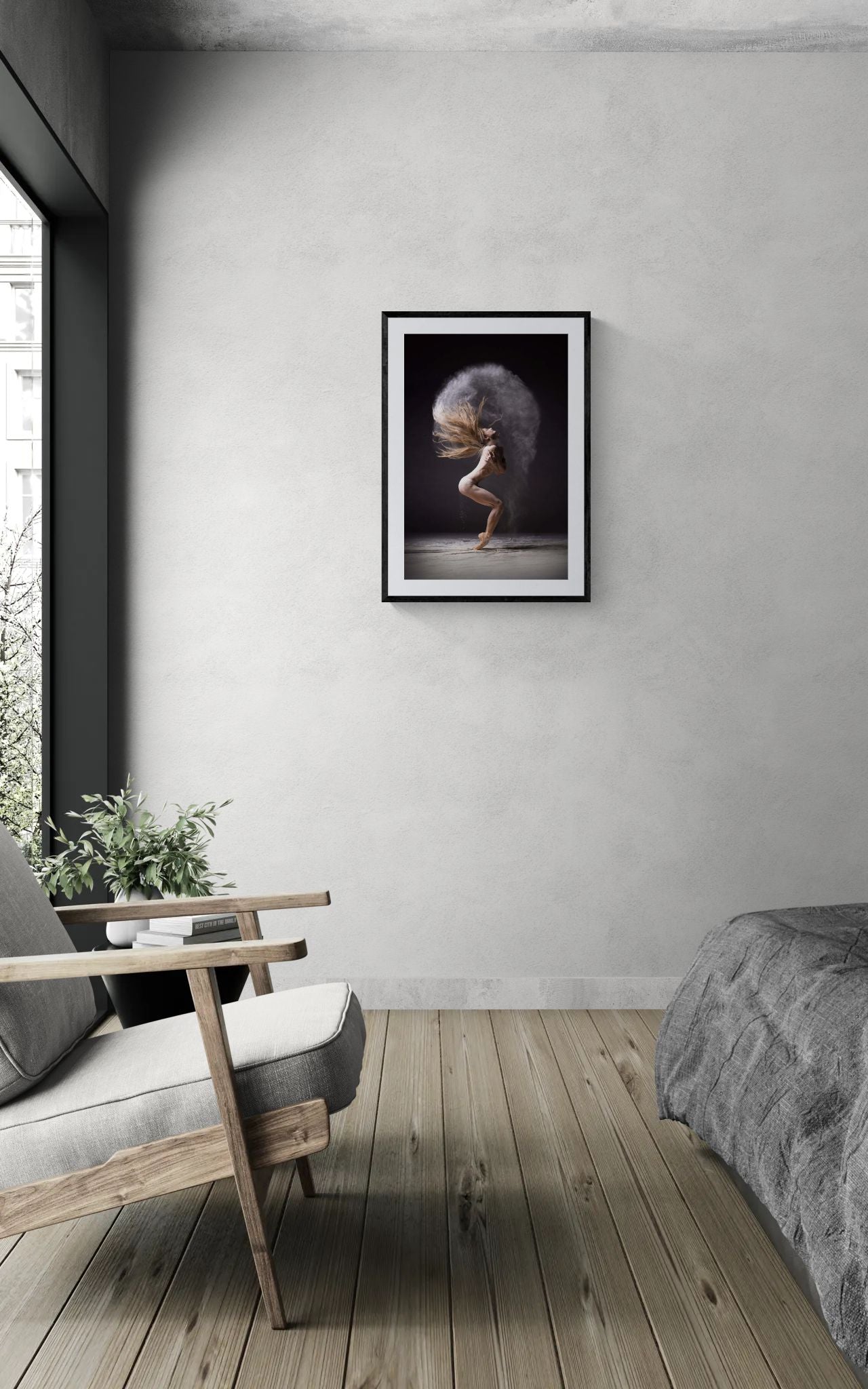 Framed Cloud Halo dance print on a light grey wall above a wooden armchair with a plant in a minimal bedroom.