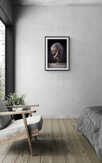 Framed Cloud Halo dance print on a light grey wall above a wooden armchair with a plant in a minimal bedroom.