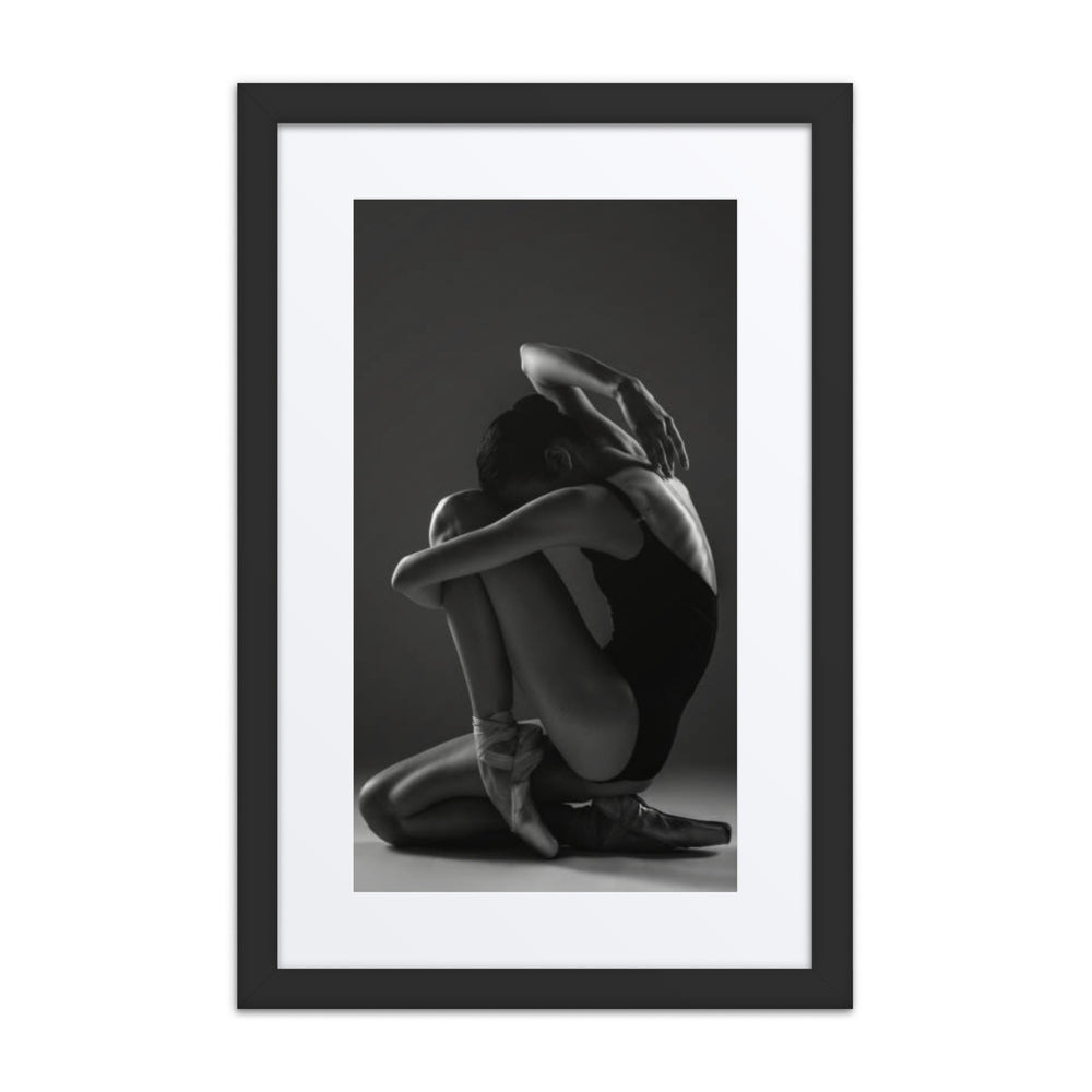 A captivating black-and-white portrait of a seated ballerina in a thoughtful pose, emphasizing grace and introspection.