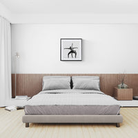 Soft neutral bedroom with low bed and wood headboard, a framed square black-and-white dance photograph hanging above.