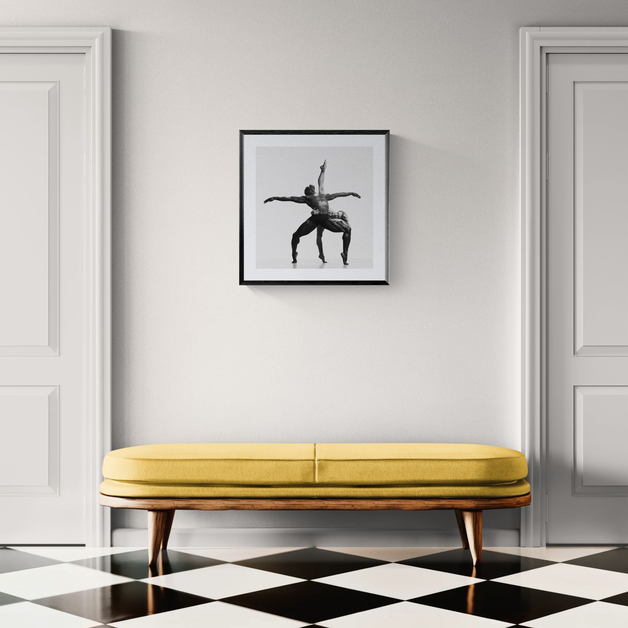 Minimal hallway with pale walls and white doors, a yellow bench below a framed square black-and-white dance photograph.