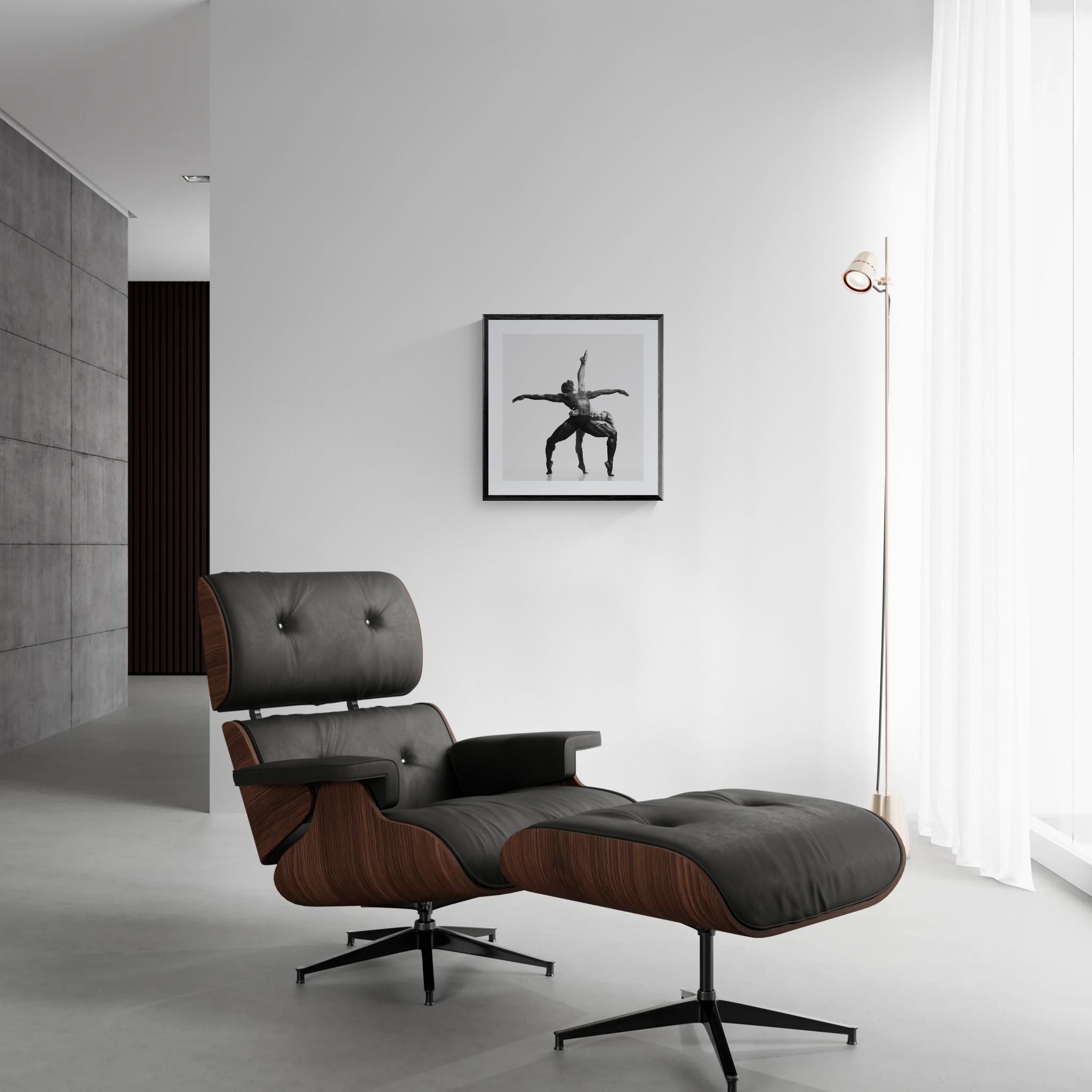Minimal living area with a modern lounge chair and floor lamp beside a framed square black-and-white dance photograph on a white wall.