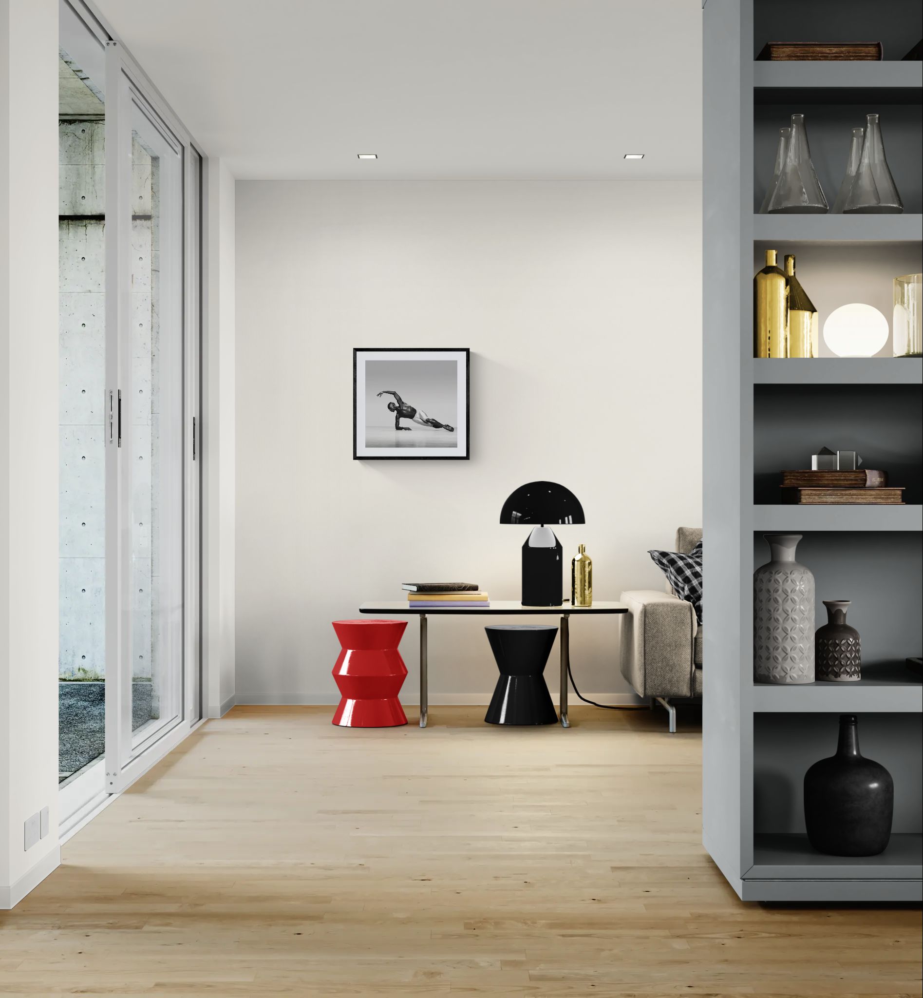 Open-plan room with sliding glass doors, a small table with red and black stools, and a framed square black-and-white dance photograph on the wall.