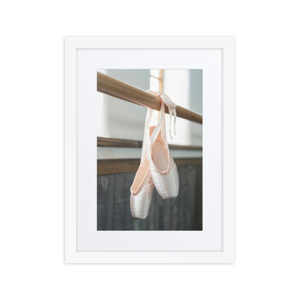 A serene photograph of satin ballet pointe shoes gracefully hanging from a barre, symbolizing dedication and artistry in the world of dance.