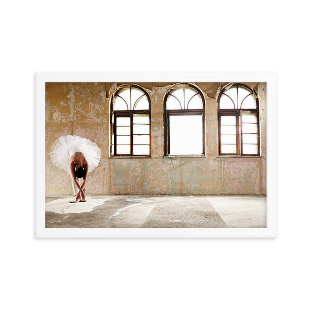 A ballerina in a delicate white tutu leans forward gracefully in a derelict room, framed by large arched windows that illuminate the faded, textured walls. The juxtaposition of the dancer's elegance against the worn surroundings creates a timeless moment of beauty and strength.