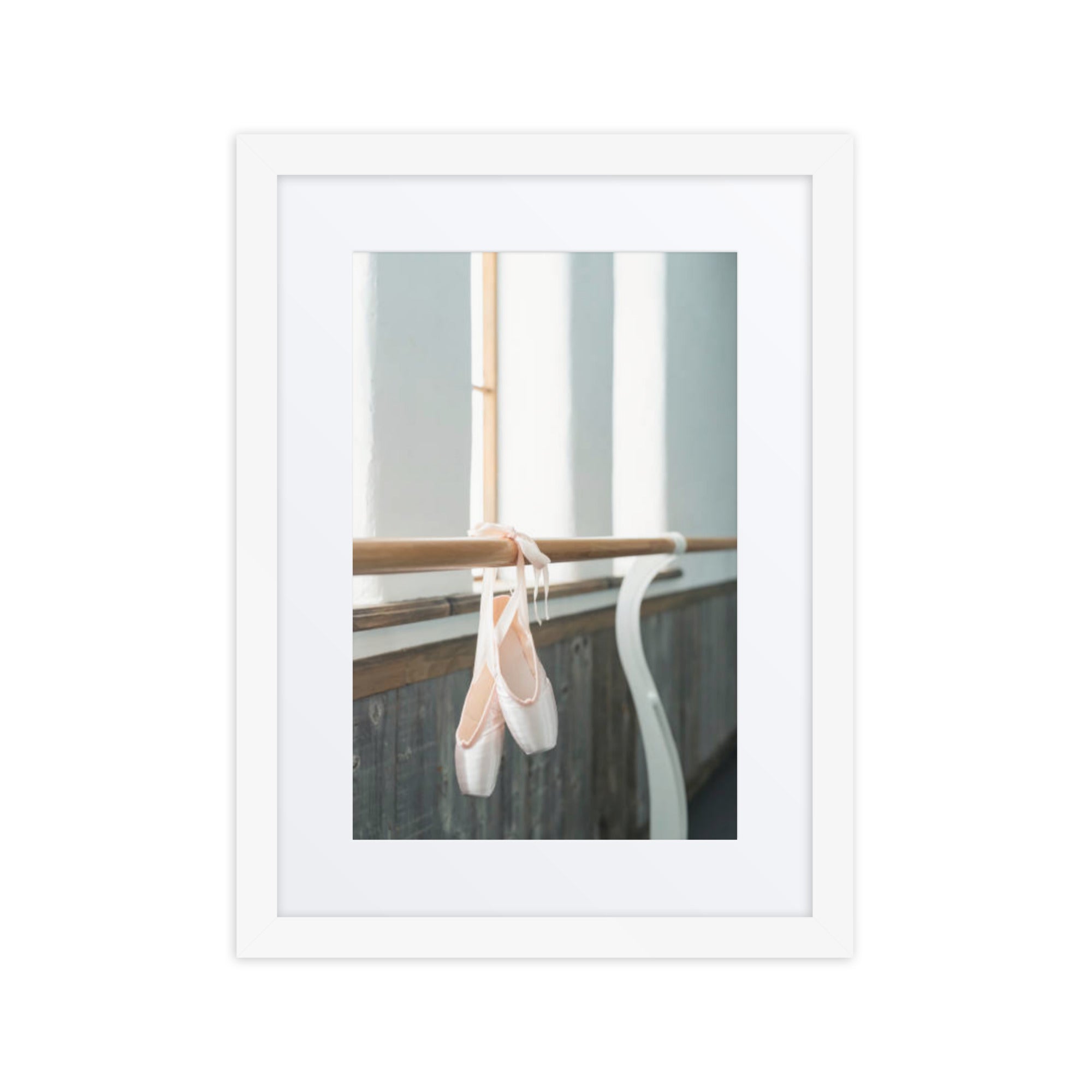 A serene image of delicate ballet pointe shoes hanging gracefully over a wooden barre, evoking a sense of calm and dedication in the dance studio.