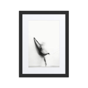 A minimalist black-and-white photograph of a ballerina in motion, evoking the silhouette of a sailboat, framed in a sleek black frame with a white border.