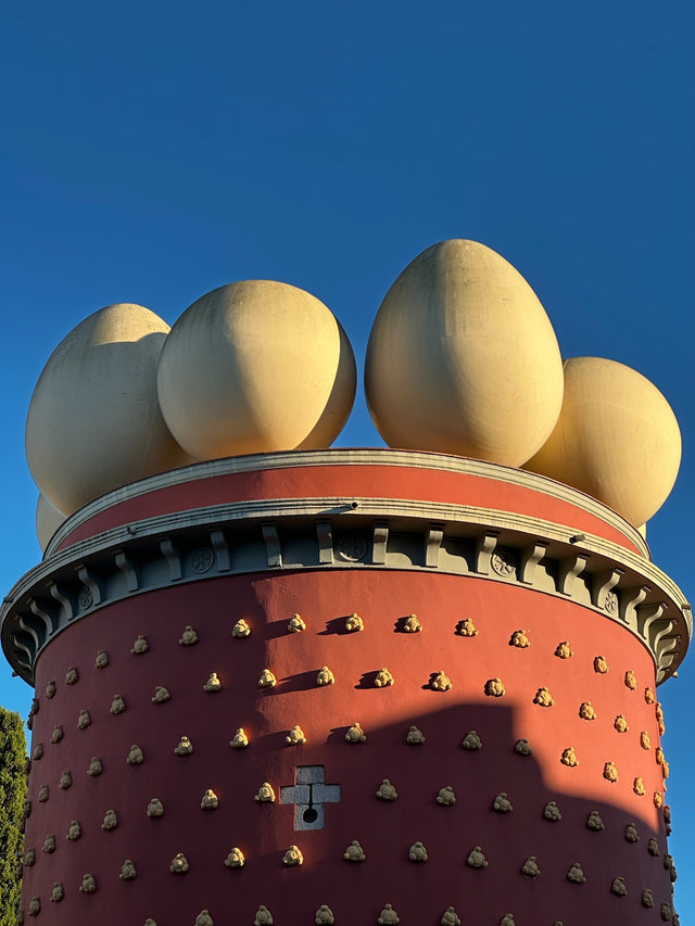 Crowned with golden eggs — symbols of creation and rebirth — the Dalí Theatre-Museum blurs architecture and mythology. Dalí transforms the ordinary into ritual, balancing humor and divinity in a single surreal gesture.