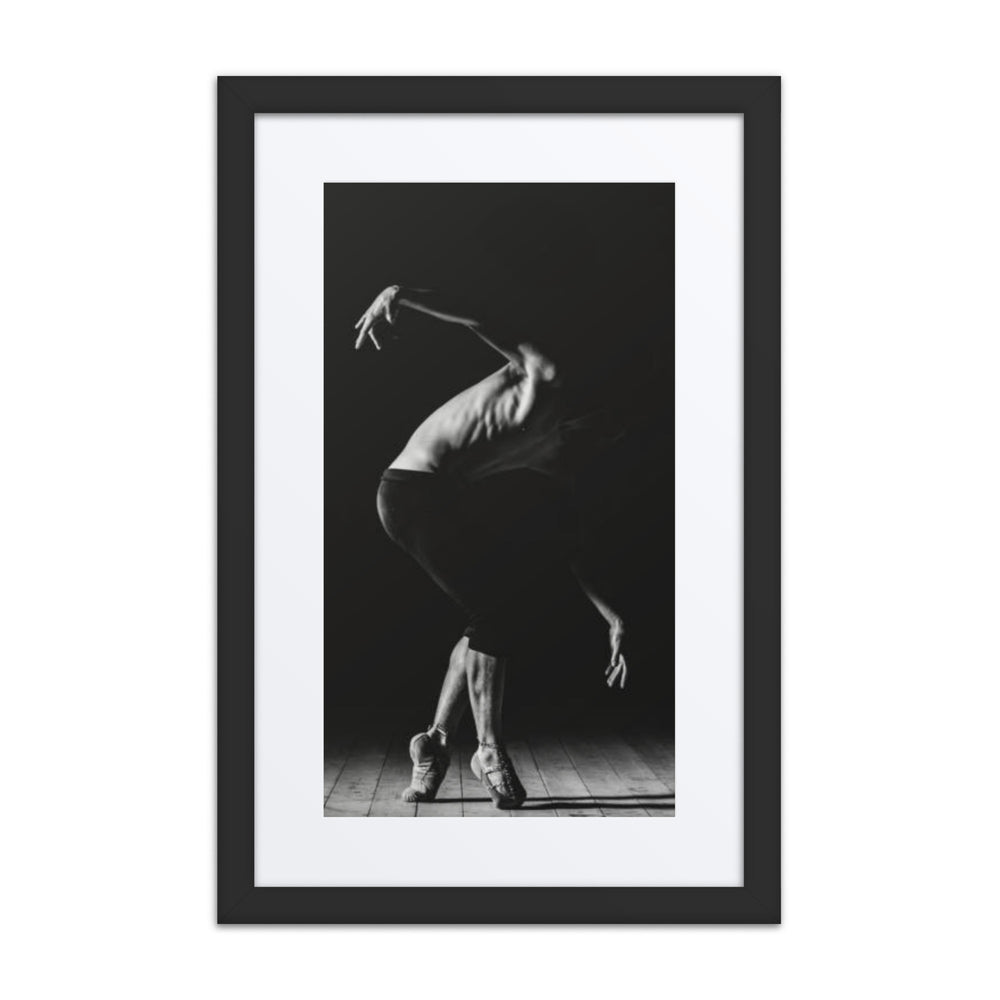 A powerful black-and-white photograph of a male dancer mid-performance, capturing his poised elegance and the interplay of shadow and light on the stage floor.