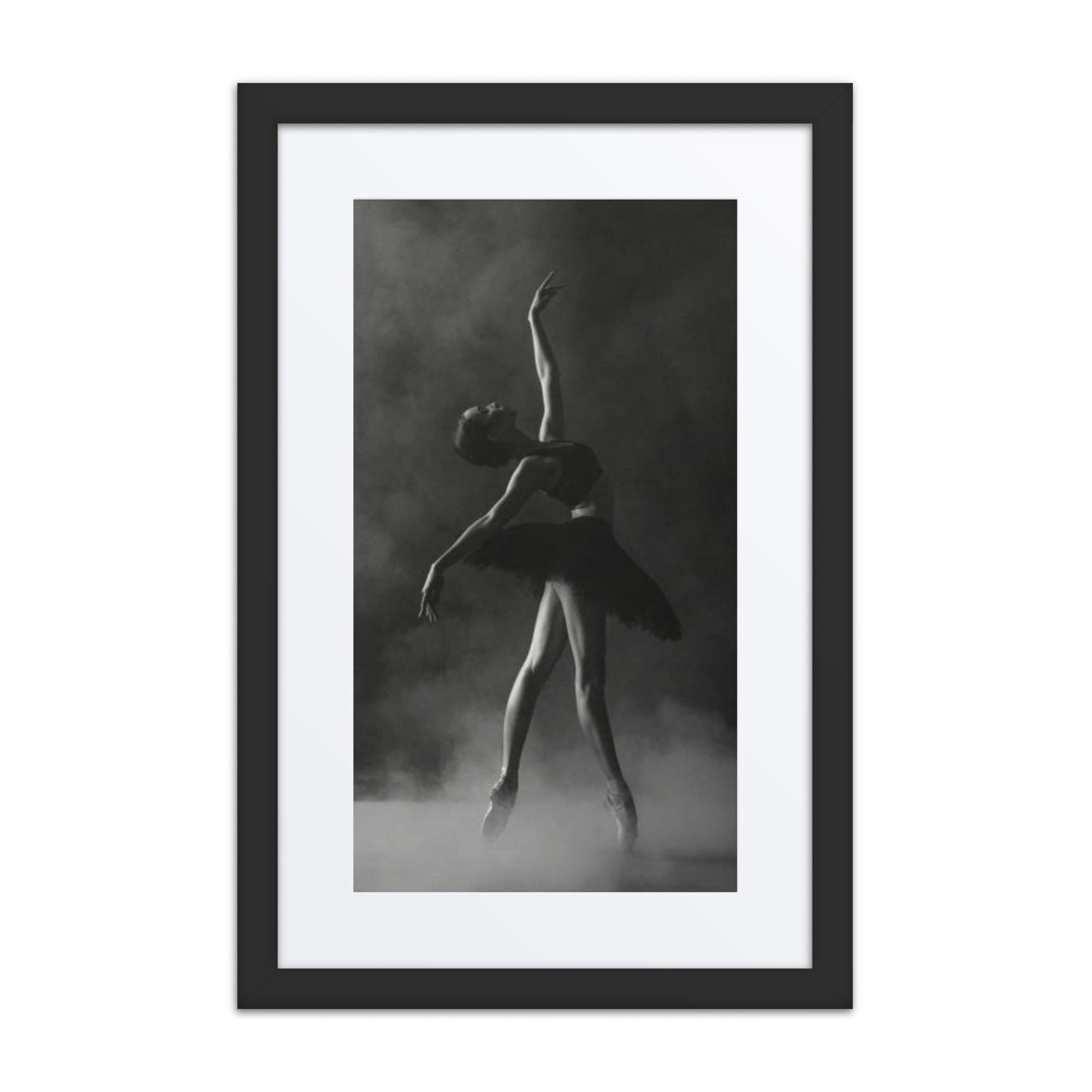 A dramatic black-and-white photograph of a ballerina poised in a graceful stretch, wearing a black tutu against a smoky background.