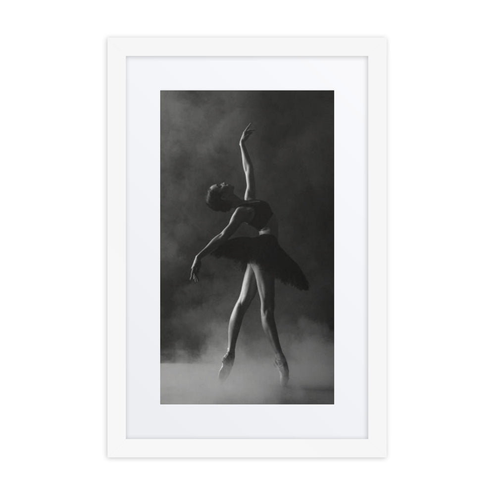 A dramatic black-and-white photograph of a ballerina poised in a graceful stretch, wearing a black tutu against a smoky background.