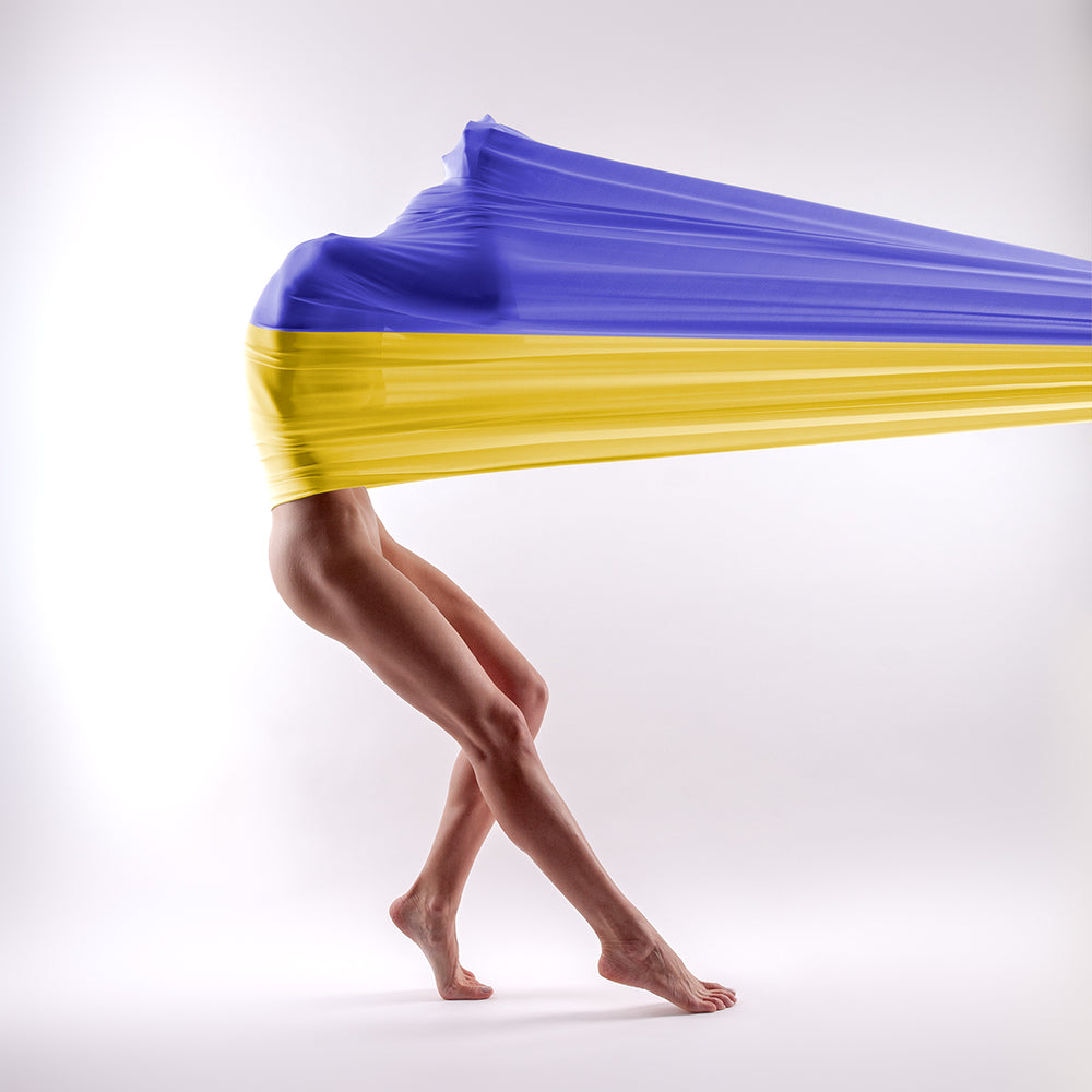 Dancer stretching her own body by a fabric with Ukraine flag - buy the photo as print and all the money will go to help the refugees.