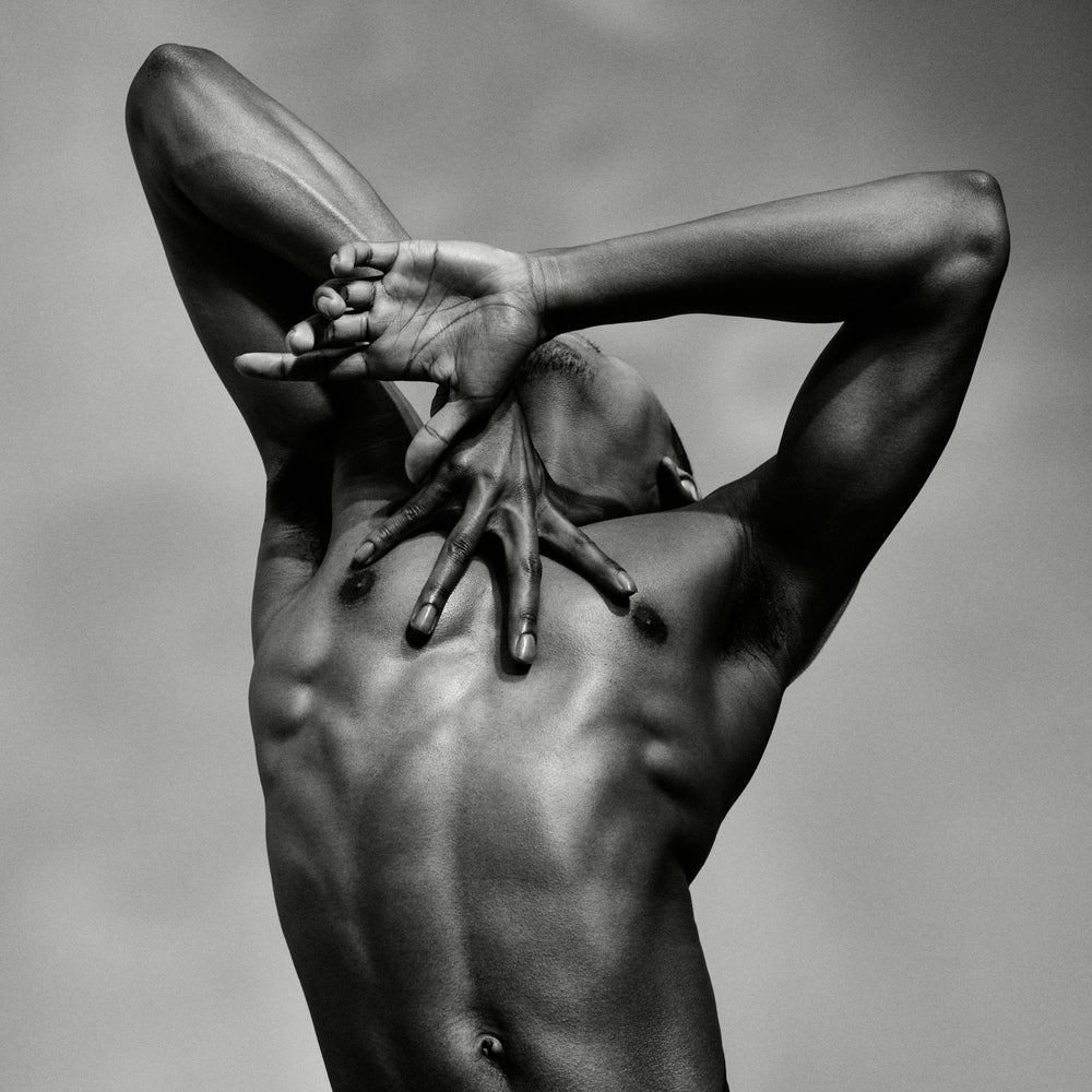 Close-up photograph of a male dancer and hands from the artwork J. by Sasha Onyshchenko, showing sculptural musculature and expressive hand placement in monochrome fine art style.