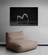 Artwork on a wall decor, beanbag below. Print image of a female gymnast, contortion, artistic, aesthetic. Photo print studio, colors black and white.